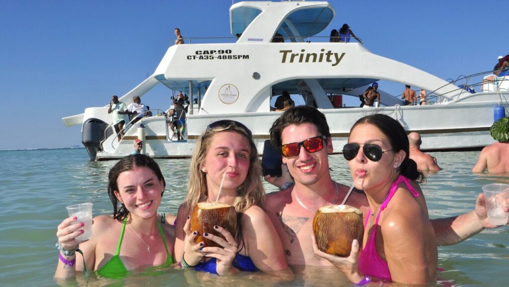Friends with coconut drinks next to the catamaran