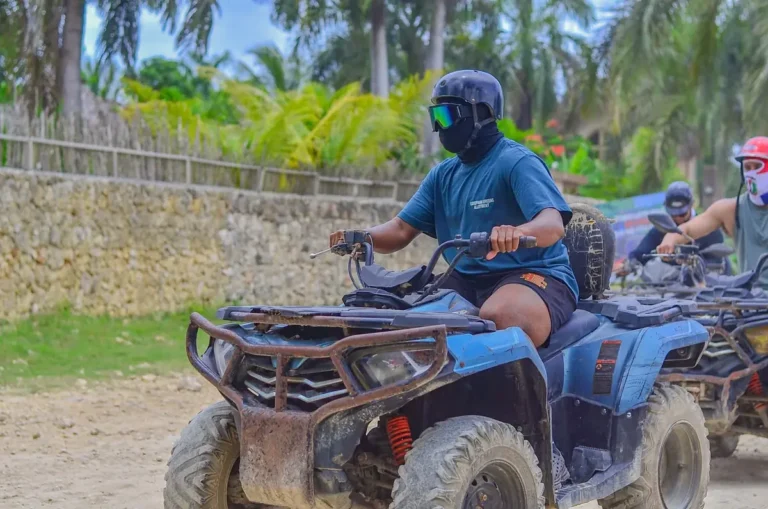 Helmeted riders on ATVs along a country road in Punta Cana