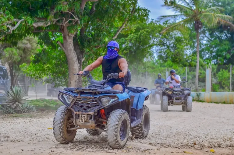 Helmeted riders on ATVs along a country road in Punta Cana