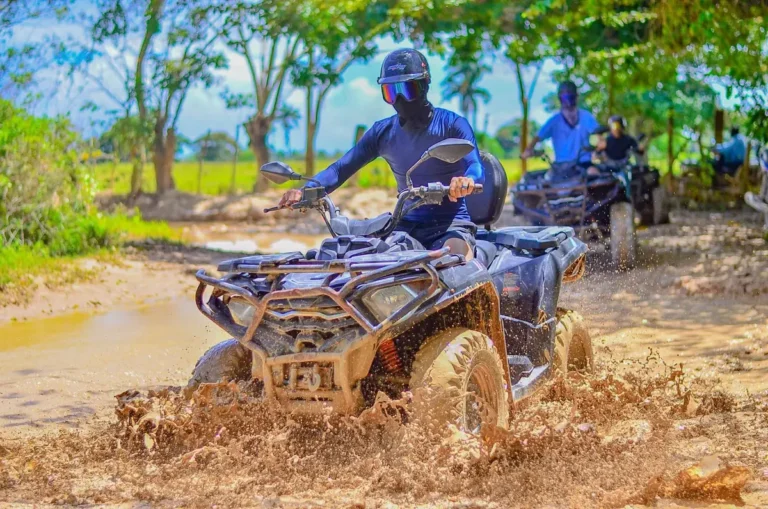 ATV sending up a spray of mud and water on the countryside trail