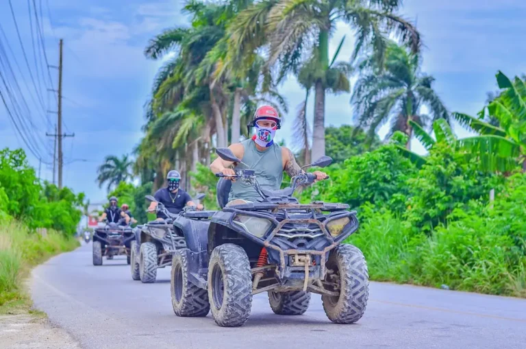 Riders on ATVs along a palm-lined trail in the Punta Cana countryside