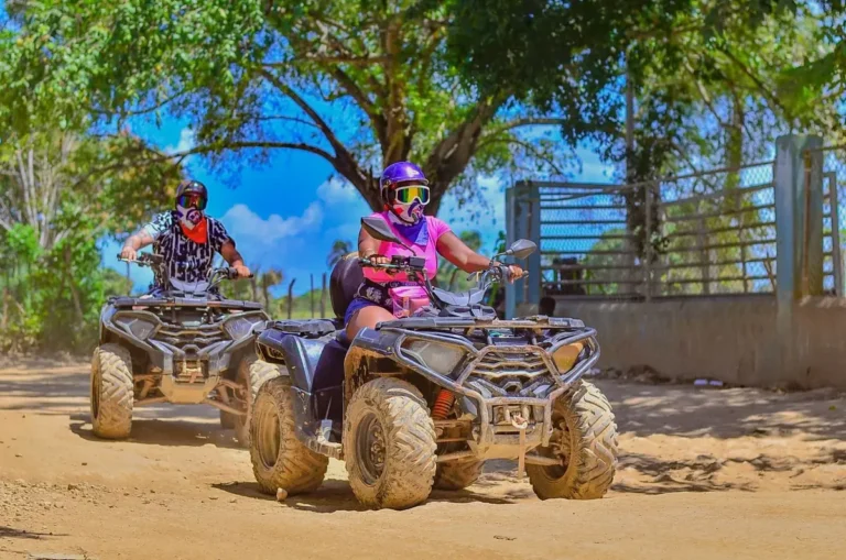 Couple in helmets riding an ATV along a dirt trail in Punta Cana