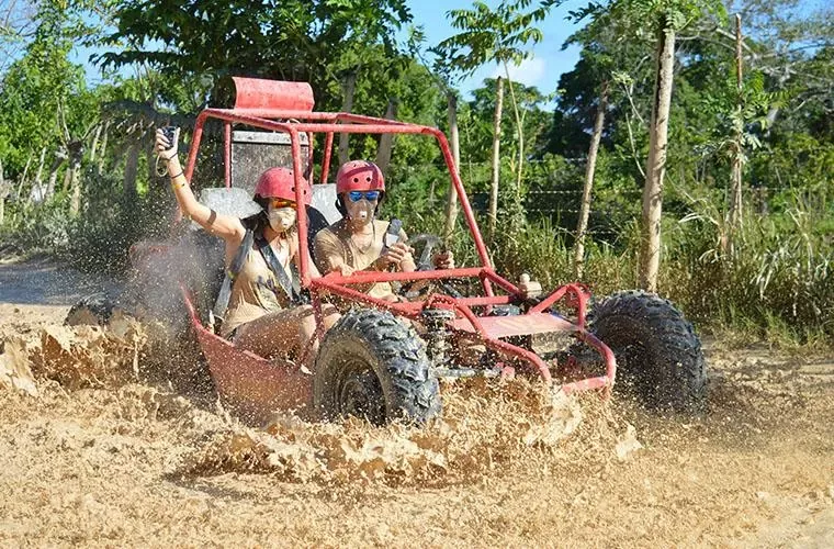 Red buggy splashing through a puddle on a country trail in Punta Cana