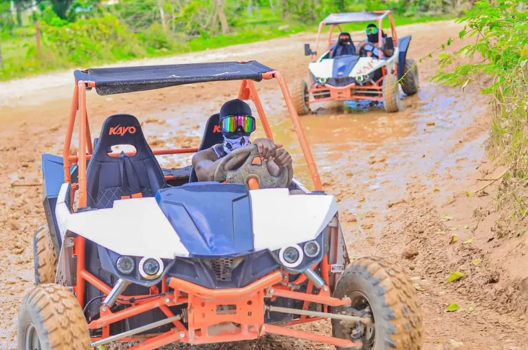 Guests in helmets driving an off-road buggy on a dirt track in Punta Cana