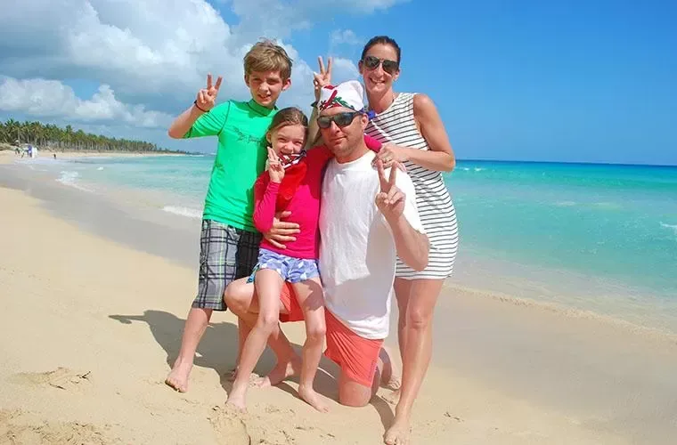 Family on a pale sand beach beside turquoise water in Punta Cana