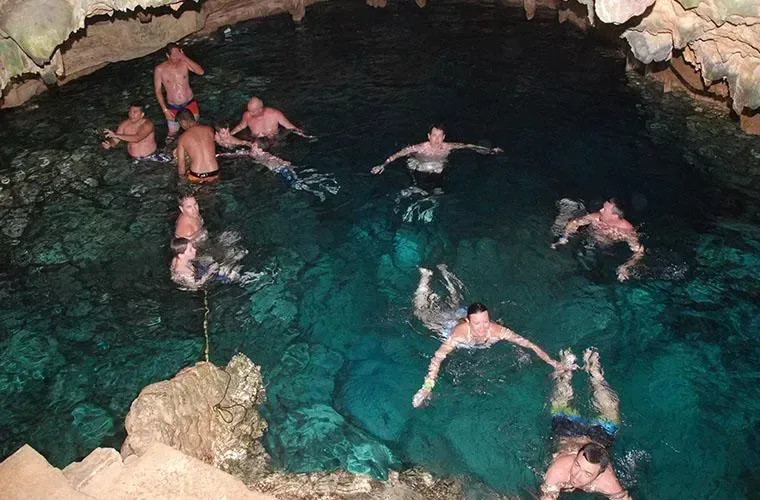 Guests swimming in the clear water of a natural rock cave