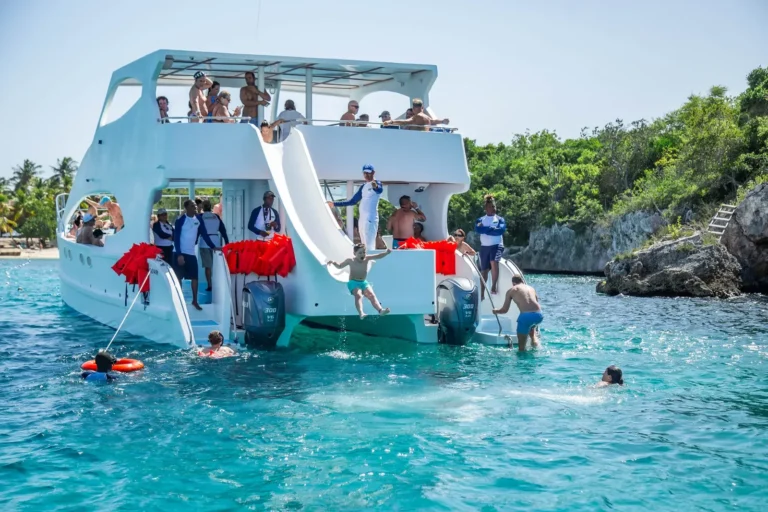 Guests jumping off the slide of a catamaran into turquoise water near Catalina Island
