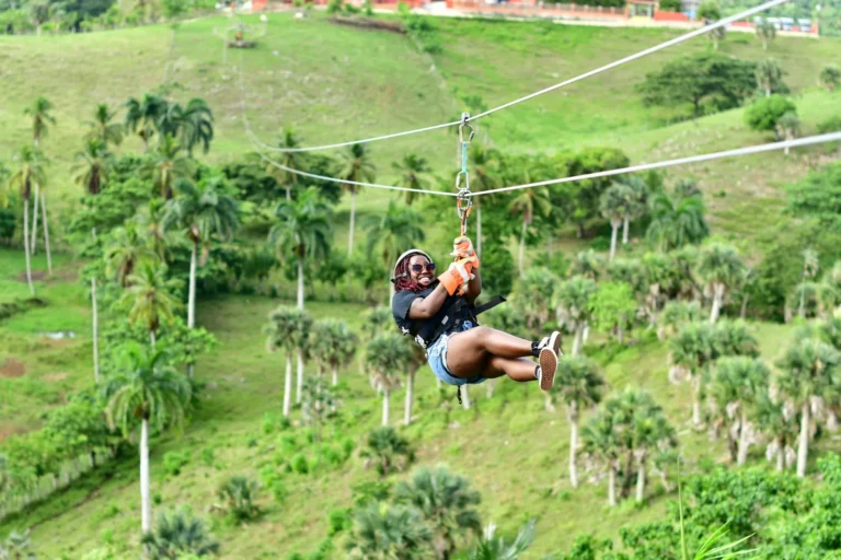 Guest riding the zipline above the palm trees at La Hacienda Park