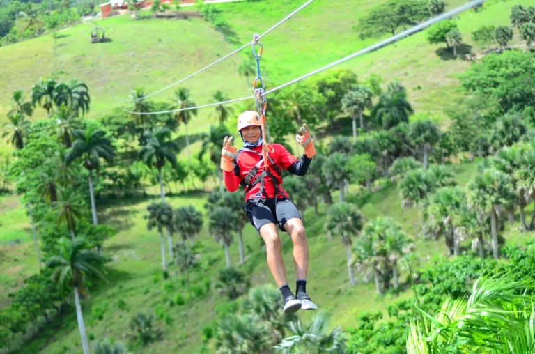 Guests on a zipline above a green valley at La Hacienda Park