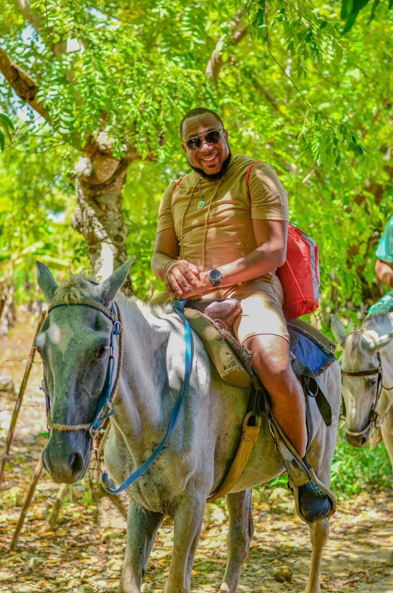 Guest smiling on a gray horse on a tropical trail