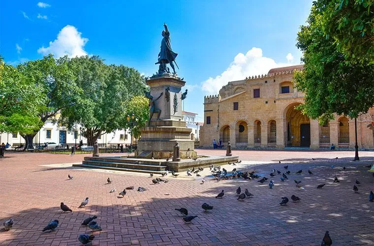 Columbus monument surrounded by trees and pigeons in Parque Colon