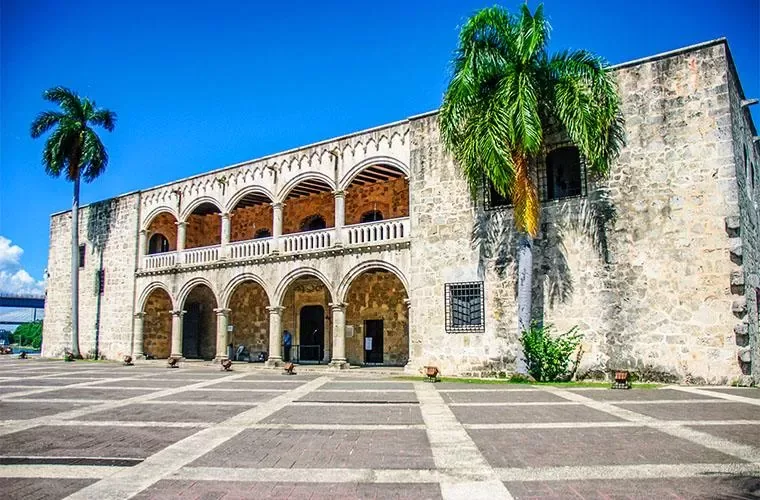 Facade of the Alcazar de Colon with arched galleries and palms in Santo Domingo