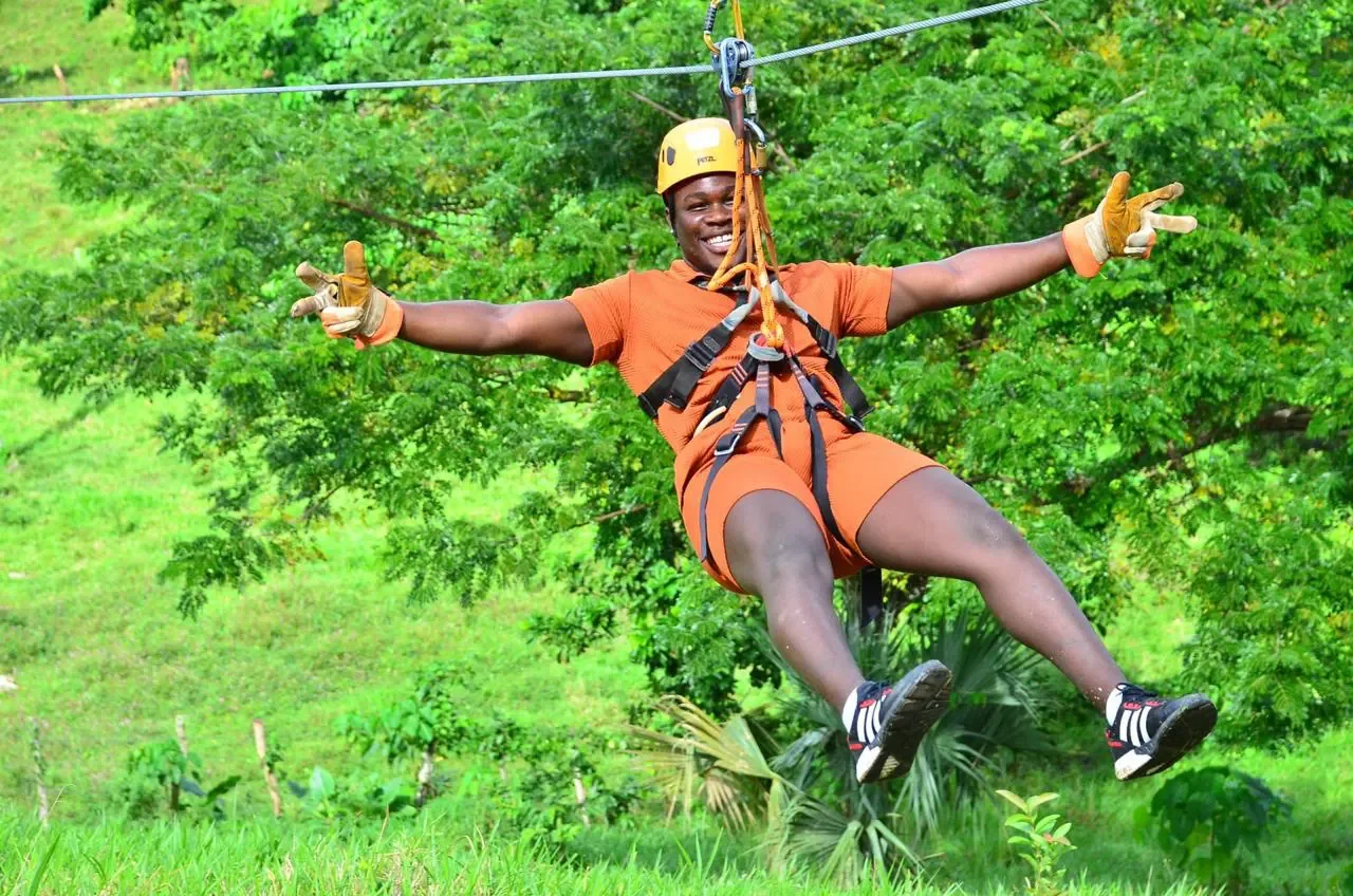 Guest flying the zipline with both arms out at the Punta Cana adventure park